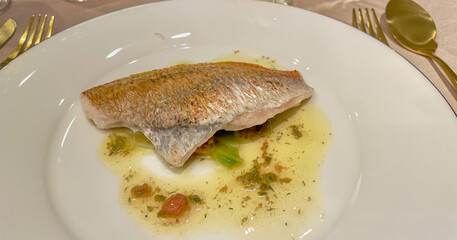 baked white fish on a plate surrounded by white sauce