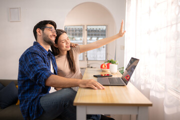 Portrait of a young freelancer smiling while working online via laptop at home with his girlfriend