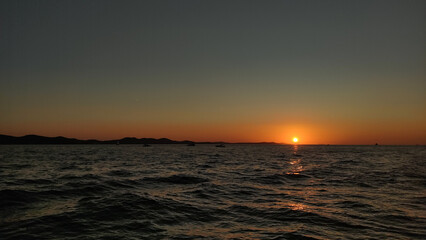 Sun setting over croatian coastline in summer evening background wallpaper copy space