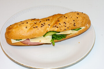 A delicious deli sandwich features layers of ham, cheese, and fresh vegetables nestled in a sesame seed roll. Perfect for lunch or a quick snack any time of day