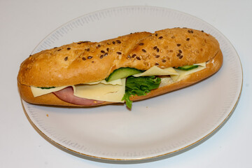 A delicious sandwich features layers of ham, cheese, and fresh lettuce, neatly arranged inside a toasted sesame seed bun. Perfect for lunch or a quick snack