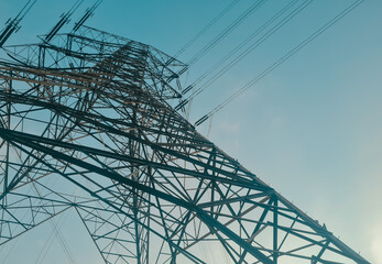View from bottom of high voltage post or tower against clear blue sky. Electricity powerline distribution to the city. abstract composition background.