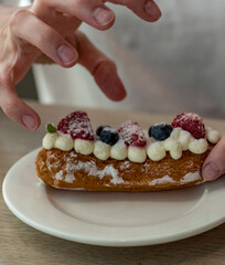 Person is holding a pastry with strawberries and blueberries on top