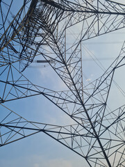 View from bottom of high voltage post or tower against clear blue sky. Electricity powerline...