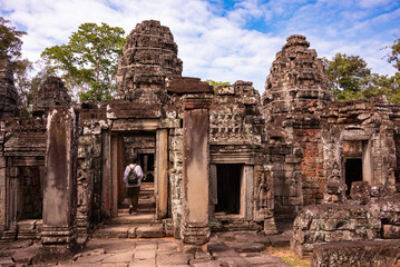 Naklejka premium Tourist entering Angkor ancient temple ruins in Cambodia