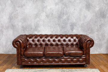 Elegant Brown Leather Sofa Against Gray Plastered Wall"