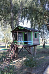 Wooden Tree house in a park with a playground.