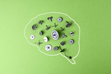 A brain outline on a green background filled with scattered metallic mechanisms, gears, and screws. A symbol of thought processes, mental well-being, and intelligence.