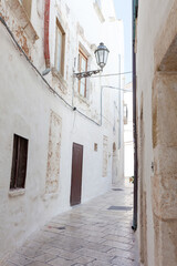 Narrow street with white buildings and stone pavement in Ostuni, Puglia, Italy