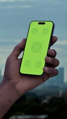 GREEN SCREEN CHROMA KEY Hand holding a phone with a city skyline in the background. Ideal for mockups of taxi, betting, or travel apps set in an urban environment