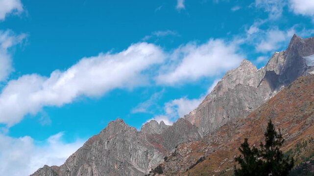 Landscape shot of clouds above the Himalayan mountain peaks against the blue sky as seen from Sangla Village in Kinnaur district, Himachal Pradesh, India. Nature background with copy space.