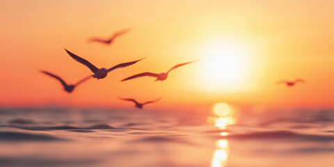 Obraz premium Seagulls gliding over ocean during vibrant sunset with golden light reflections peaceful seascape