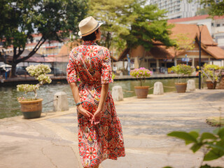 woman in dress and hat exploring vibrant streets of Malacca, Malaysia.