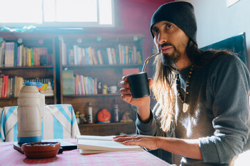 Argentinian man at home drinking mate and looking ahead thinking analyzing what he read in the book