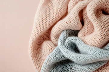 Soft knitted sweaters in pastel colors arranged neatly on a light background