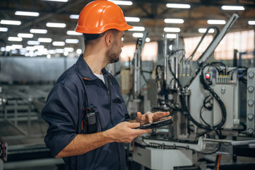 Machinery conception, operator is with tablet. Man is working in the modern factory