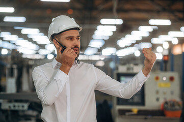 Talking by a walkie talkie. Man is working in the modern factory