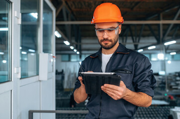 Contractor is with digital tablet. Man is working in the modern factory