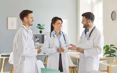 Joyful team of positive doctors and nurses works together in a hospital office during a meeting, discussing tasks and fostering teamwork. Collaboration and professional dedication.