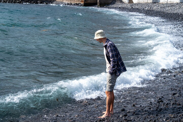 Introspective man stands knee-deep in turquoise waters, Coastal wanderer in checkered shirt and...