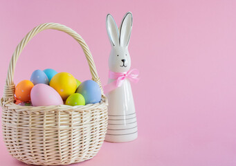 Basket with colorful Easter eggs on a pink background, copy space. High quality photo