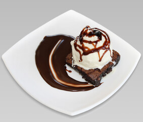 brownie with vanilla ice cream and chocolate sauce on a white background