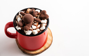 Red ceramic mug with a hot drink with marshmallows decorated with a chocolate bear, copy space