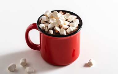 A red mug with a hot drink and marshmallows on a white table