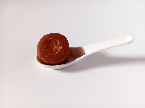 Coconut sugar aka coconut palm sugar, java sugar is a natural sweetener derived from the sap of the flower buds of the coconut tree in ceramic spoon isolated on white plate background.