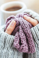 Embrace the Cozy Vibe: A Close-Up of Knitting in Sweater Hands near a Warm Drink for Craft Lovers and Winter Enthusiasts