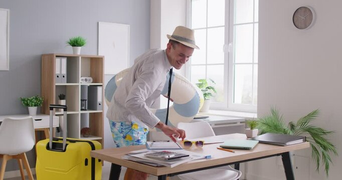 Portrait of happy young funny man employee wearing beach hat, shorts and shirt finishing job and leaving office going on summer vacation trip. Travel and holiday concept. 4k video. Slow motion video.