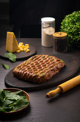 Cheese ruddy pie with spinach on a dark wooden table