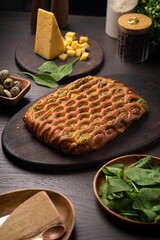 Cheese ruddy pie with spinach on a dark wooden table