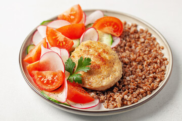 Chicken cutlet with buckwheat porridge and vegetable salad in a plate on the table. Healthy food