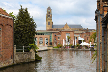 Vista del canal de Brujas, Bélgica, con la torre de la catedral destacando entre edificios...