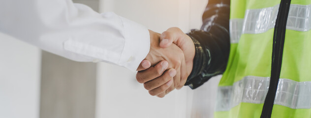 construction worker and contractor. Client shaking hands with team builder in renovation site.
