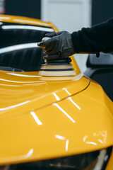 Process of polishing yellow sport car in workshop