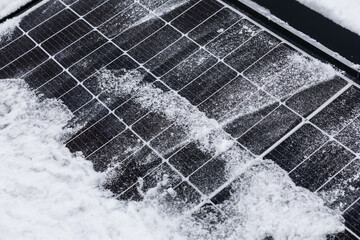 Snow-covered solar panels on rooftop struggle to absorb sunlight efficiently in winter conditions,...