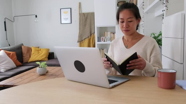 Asian freelancer woman working from home taking notes