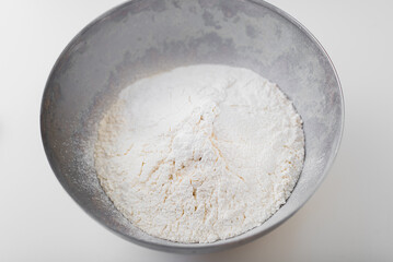 Wheat flour in a metal bowl on a white background