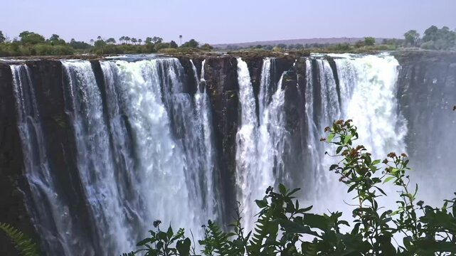 footage of the foamy stream of Devil's Pool Victoria Falls surrounded by lush landscape and blue sky