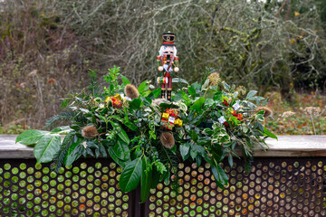 outdoor christmas arrangement made from laurel fir and green leaves with a nutcracker soldier