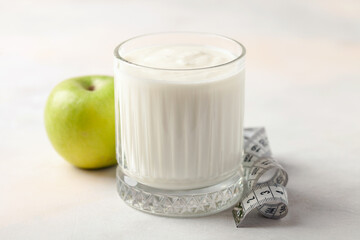 Glass of yogurt, apple and measuring tape on the table. Diet nutrition