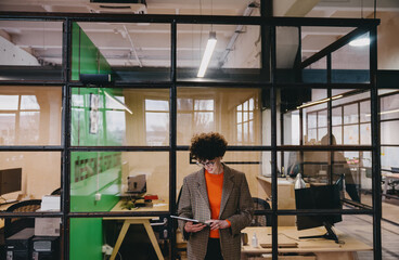 Young woman standing while working with tablet in modern office