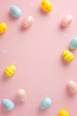 Colorful vertical Easter eggs arranged on a soft pink background, evoking festive cheer