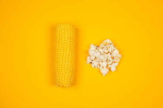 Een minimalistische compositie met een kolf ma&iuml;s en een stapel vers gepopte popcorn tegen een felgele achtergrond, die de transformatie van ma&iuml;s naar popcorn symboliseert.
