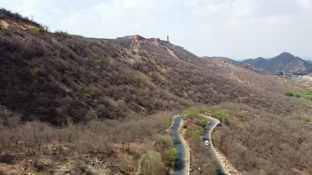 Aerial or Drone view of Aravalli mountain range in Jaipur city of India showing the beautiful landscape along with vehicles on the road 