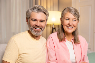 Mature couple spending time together at home and eating popcorn.