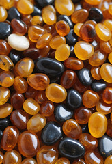 Smooth polished amber and black stones in close-up, showing glossy surfaces and rich colors. Natural gemstone collection concept