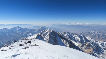 Obraz premium Panoramic view of snow-capped mountain range under a clear blue sky.